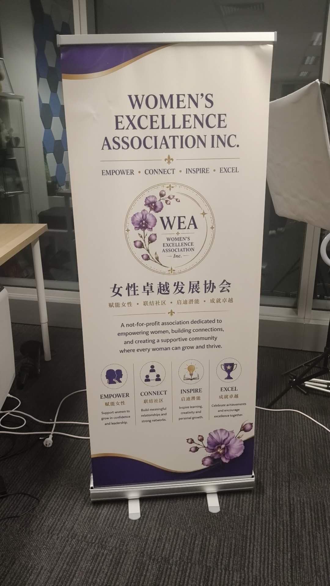 Women's Excellence Association's community banner displaying its orchid emblem and four values: empower, connect, inspire and excel